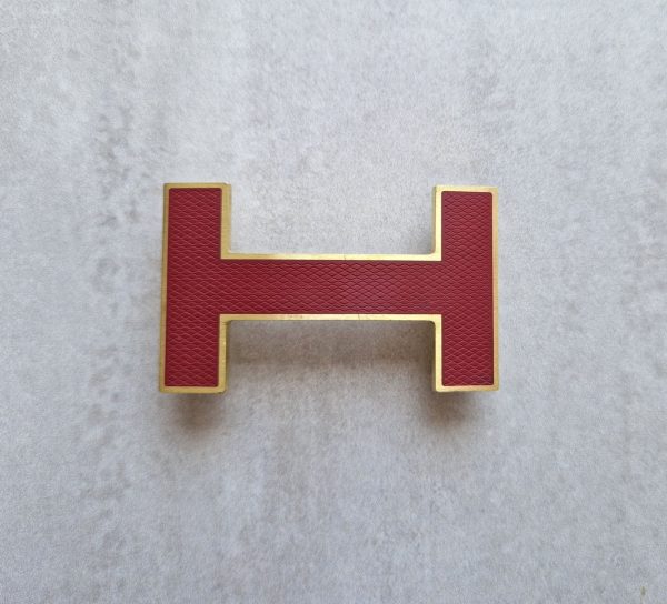 Boucle de ceinture Hermès Quizz en métal rouge et doréBoucle de ceinture Hermès Quizz en métal rouge et doré